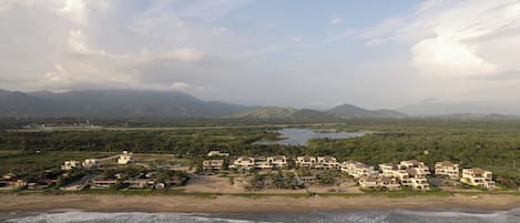 Une station balnéaire dotée de villas en bord de mer, d’une plage et d’un paysage montagneux en arrière-plan.