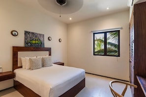 A bedroom with a bed, bedside tables, a window with a view, and a ceiling fan.