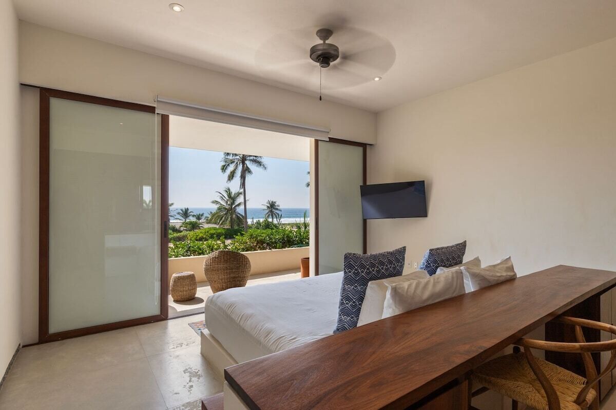 Une chambre avec un lit, une table en bois et une vue sur l’océan.