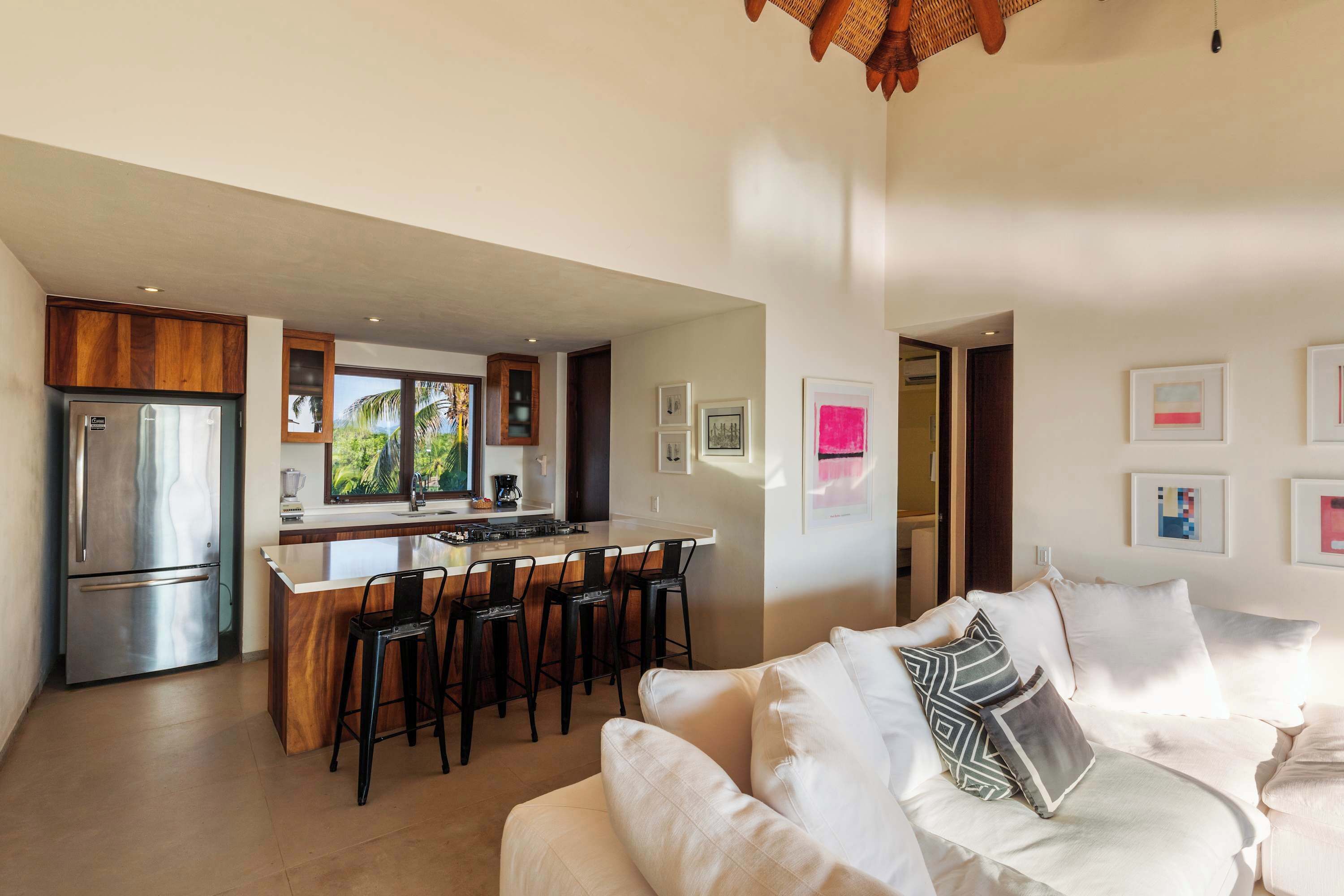 A modern kitchen with a central island, bar stools, and a refrigerator.