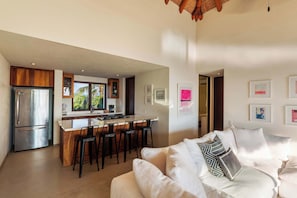 A modern kitchen with a central island, bar stools, and a refrigerator. - 1BR Boutique Villa • Pool + Beach Access (Zihuatanejo)