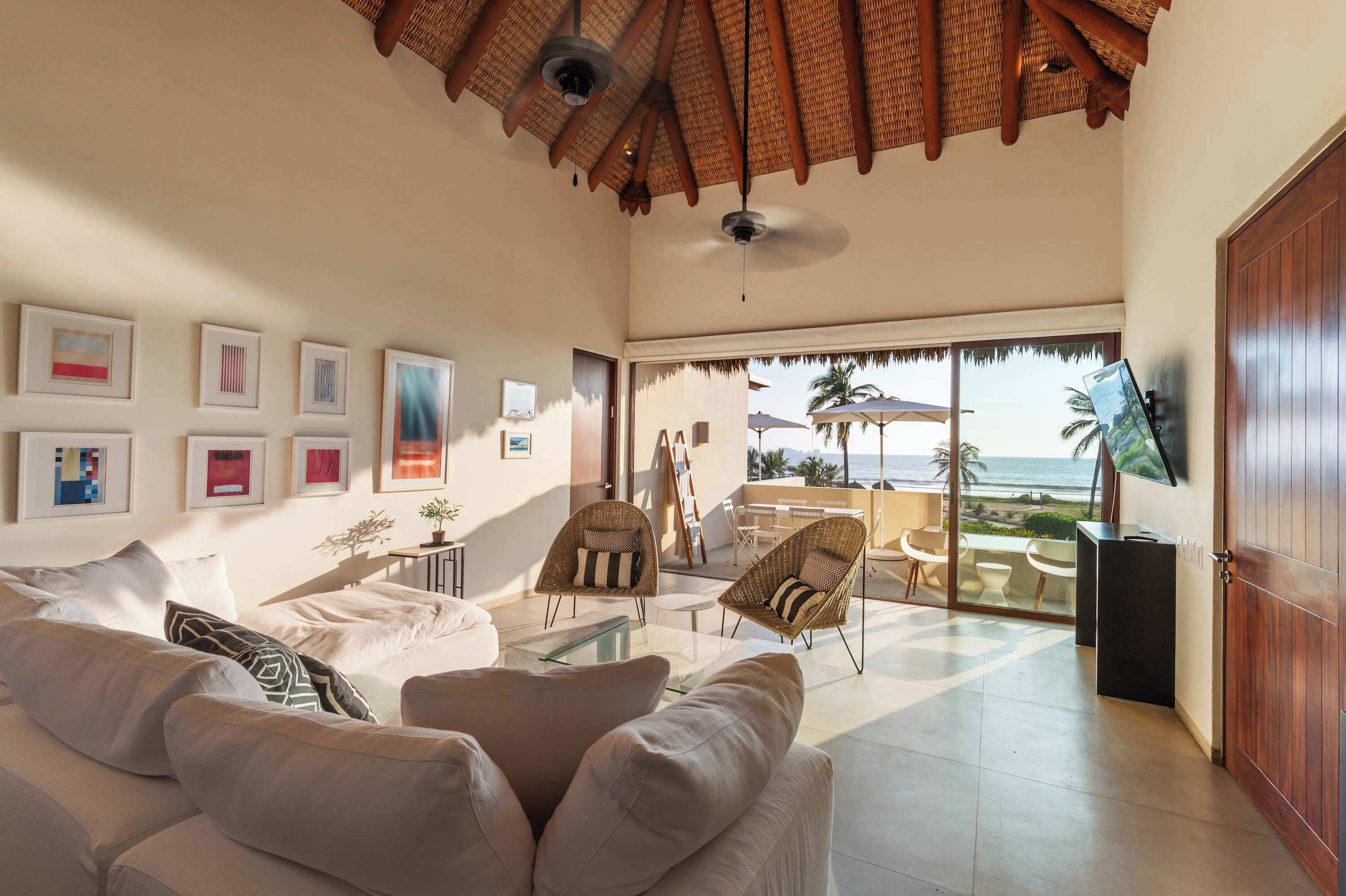 A spacious living area with a large sofa, a dining table, and a view of the ocean.