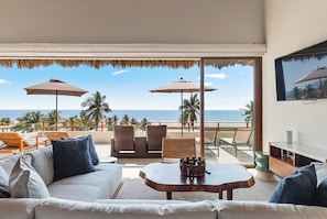 A room with a view of the beach, furnished with a sofa, chairs, and a table. - 4BR Villa Playa Blanca – Infinity Views & Comfort (Zihuatanejo)