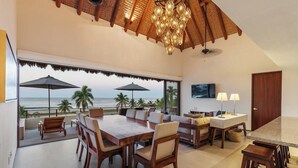 A spacious living area with a large wooden table, comfortable seating, a TV, and a view of the ocean. - 4BR Villa Playa Blanca – Infinity Views & Comfort (Zihuatanejo)