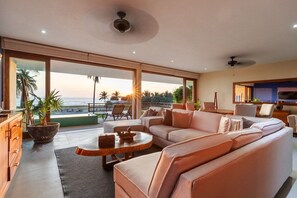 Ein modernes Wohnzimmer mit einer Couch, einem Couchtisch und Blick auf den Ozean.
