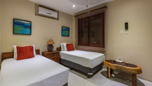 A hotel room with two beds, a small table, an air conditioning unit, and a window with blinds. - 3BR Villa I Breathtaking Ocean Views + Terrace (Zihuatanejo)