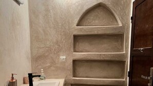 A bathroom with a sink, a mirror, a soap dispenser, and a door. - Sun & surf studio (Tamraght)