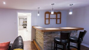 Cozinha com bancada de madeira e painel de pedra, área de refeições com mesa e cadeiras, e corredor que dá para outro quarto.