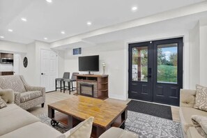 Un salon moderne avec une cheminée, un canapé, une table basse et un téléviseur.