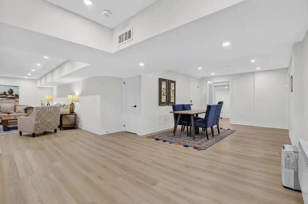 A spacious living room with a high ceiling, a dining area with a table and chairs, and a sofa set.
