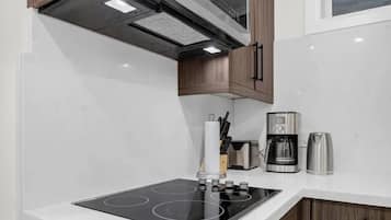 Een moderne keuken met een inbouwfornuis, koffiezetapparaat en houten kastjes.