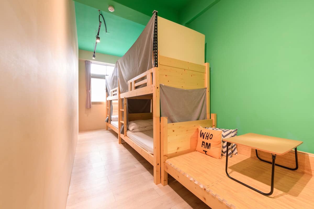 A dormitory room with bunk beds, a desk, and a chair.