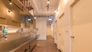 A hotel corridor with a long, stainless steel sink, multiple doors, and overhead lighting. - Dumbo Hostel Hualien (Hualien City)