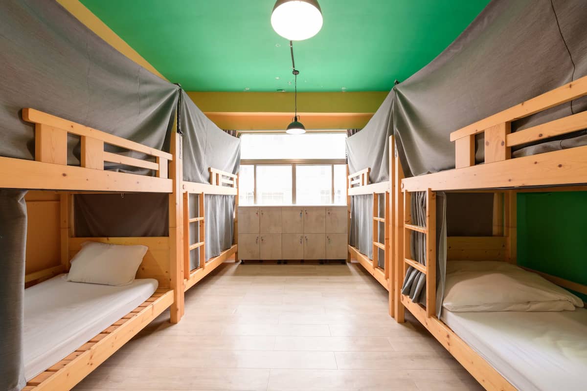 A room with bunk beds, a green ceiling, and a window with curtains.