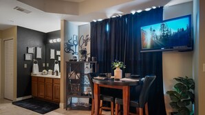 A modern kitchen with a dining area, a coffee station, and a TV mounted on the wall. - Perfectly Romantic in Branson Charming 1-bedroom condo-Jacuzzi Tub-No Stairs (Branson)