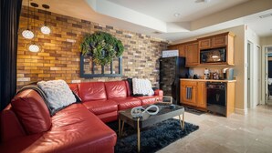 A modern living room with a red leather sofa, a black rug, and a kitchen area with wooden cabinets and appliances. - Perfectly Romantic in Branson Charming 1-bedroom condo-Jacuzzi Tub-No Stairs (Branson)
