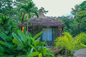 A thatched-roof hut surrounded by lush tropical vegetation. - Arenal Palms (Peñas Blancas)