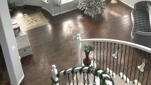 Un salon spacieux avec un grand sapin de Noël, de hauts plafonds et de nombreuses fenêtres.