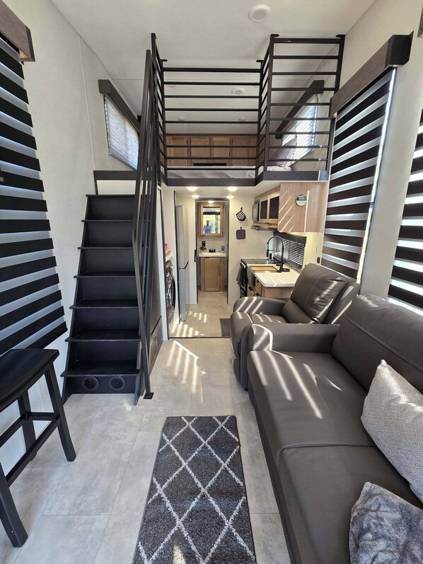 A compact living space with a staircase, a sofa, a kitchen area, and a laundry area. - Kickin' BASS at Lake Fork - Boat Ramp (Quitman)