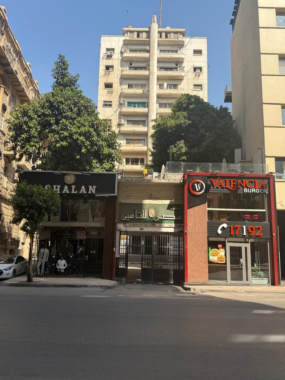 Straßenansicht mit einem Gebäude, das Schilder für 'Valencia Burgers' und 'Shalan' zeigt.