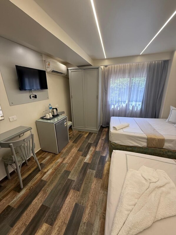 Een hotelkamer met een bed, een bureau met stoel, een aan de muur bevestigde televisie en een kledingkast.