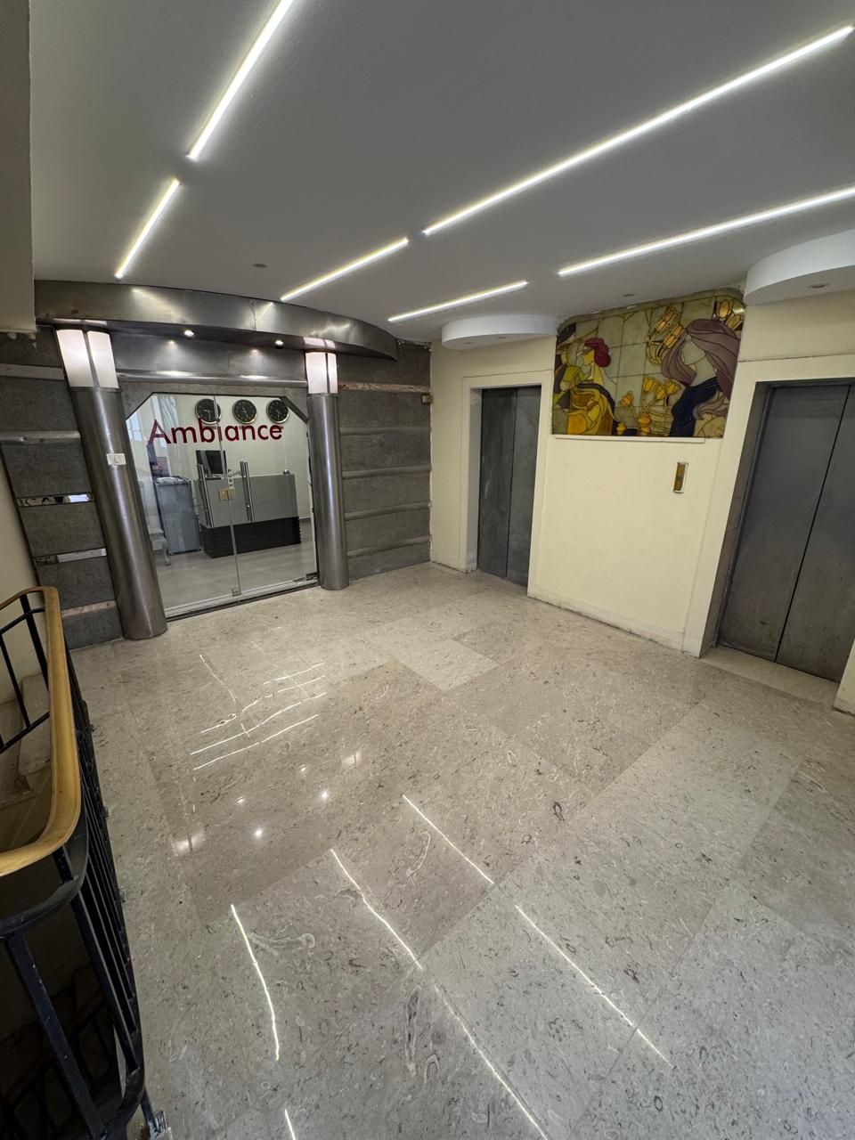 A lobby with a reception desk, a glass door entrance, and a tiled floor.