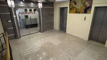 A lobby with a reception desk, a glass door entrance, and a tiled floor.
