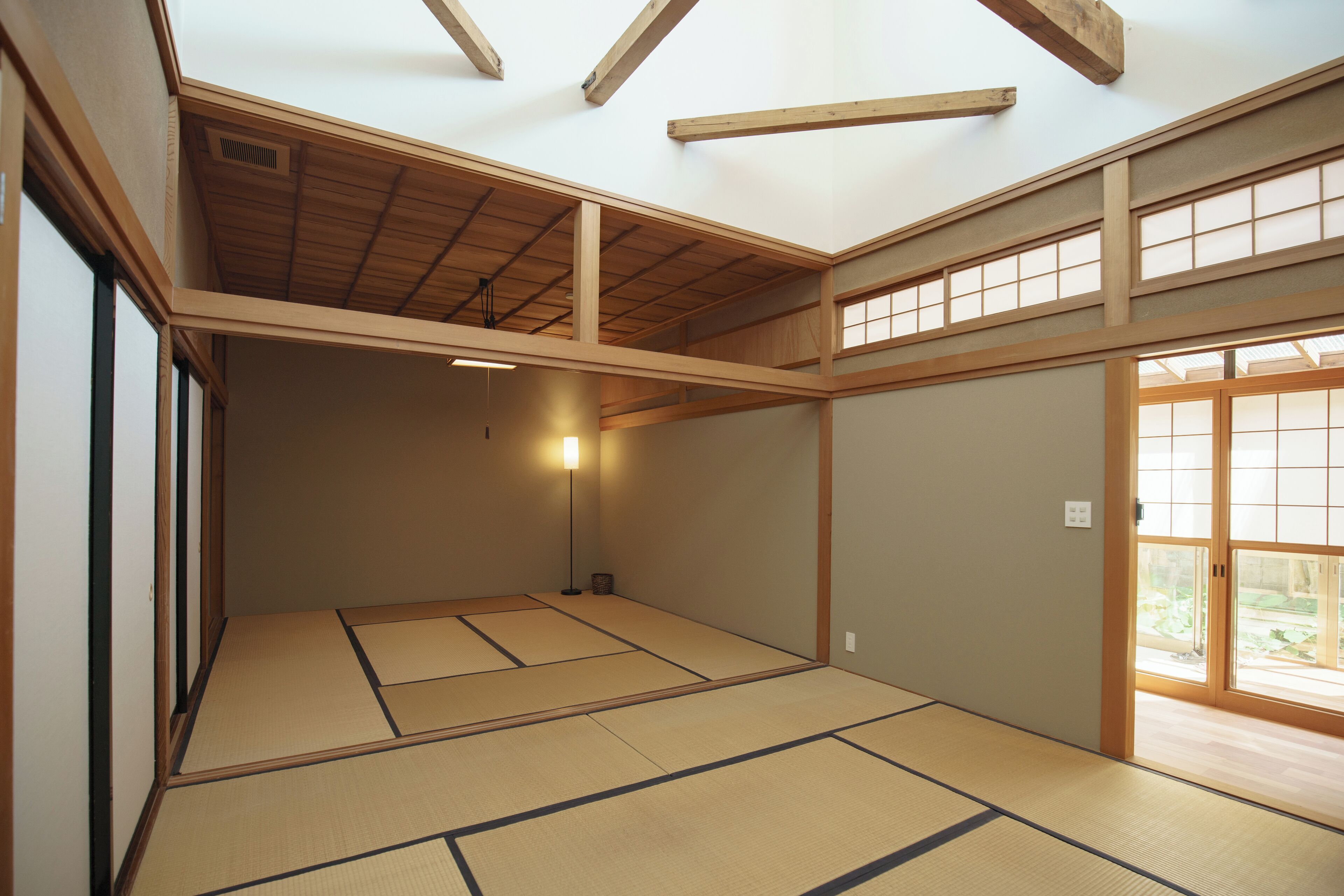 A traditional Japanese room with tatami flooring, wooden beams, and sliding doors.