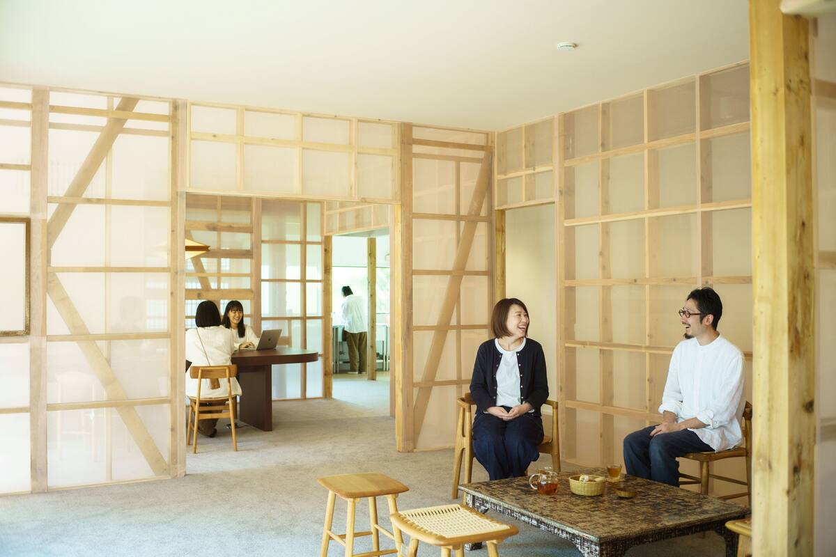 A room with a wooden partition wall, a small table with a cup and saucer, and two chairs.