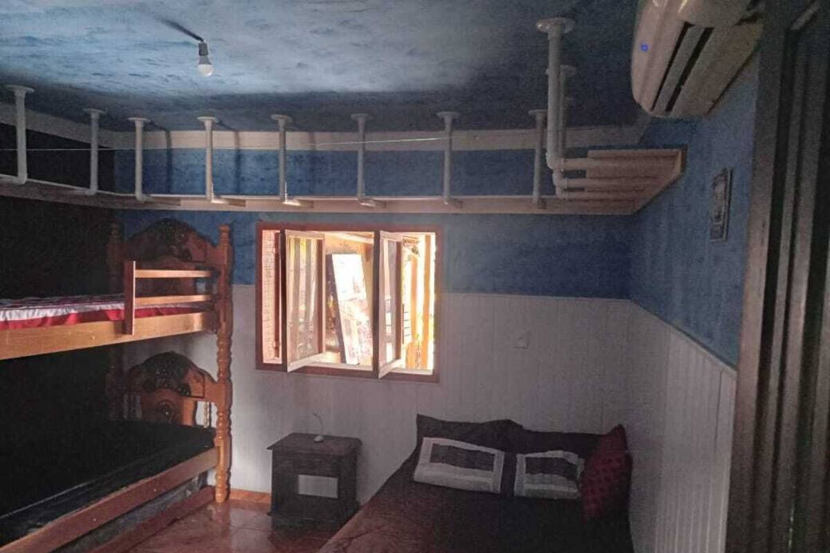 A room with bunk beds, a small table, and a window with curtains.