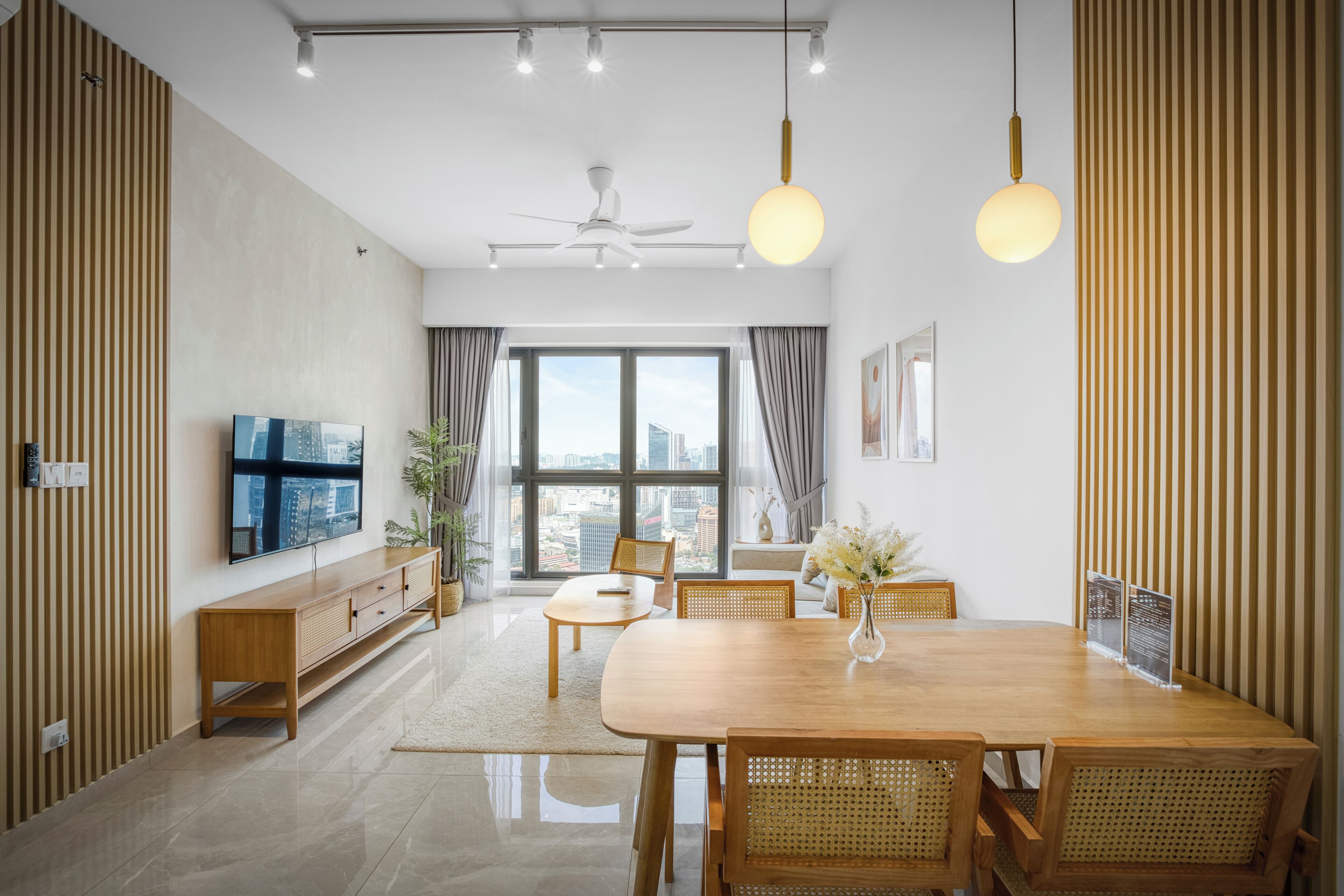 Ein modernes Wohnzimmer mit einem Holzesstisch, Stühlen, einem Fernseher und einem großen Fenster mit Blick auf die Stadt.
