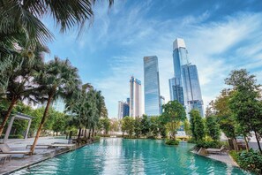 A swimming pool surrounded by palm trees and modern buildings in the background. - Ayatt Bukit Bintang (Kuala Lumpur)