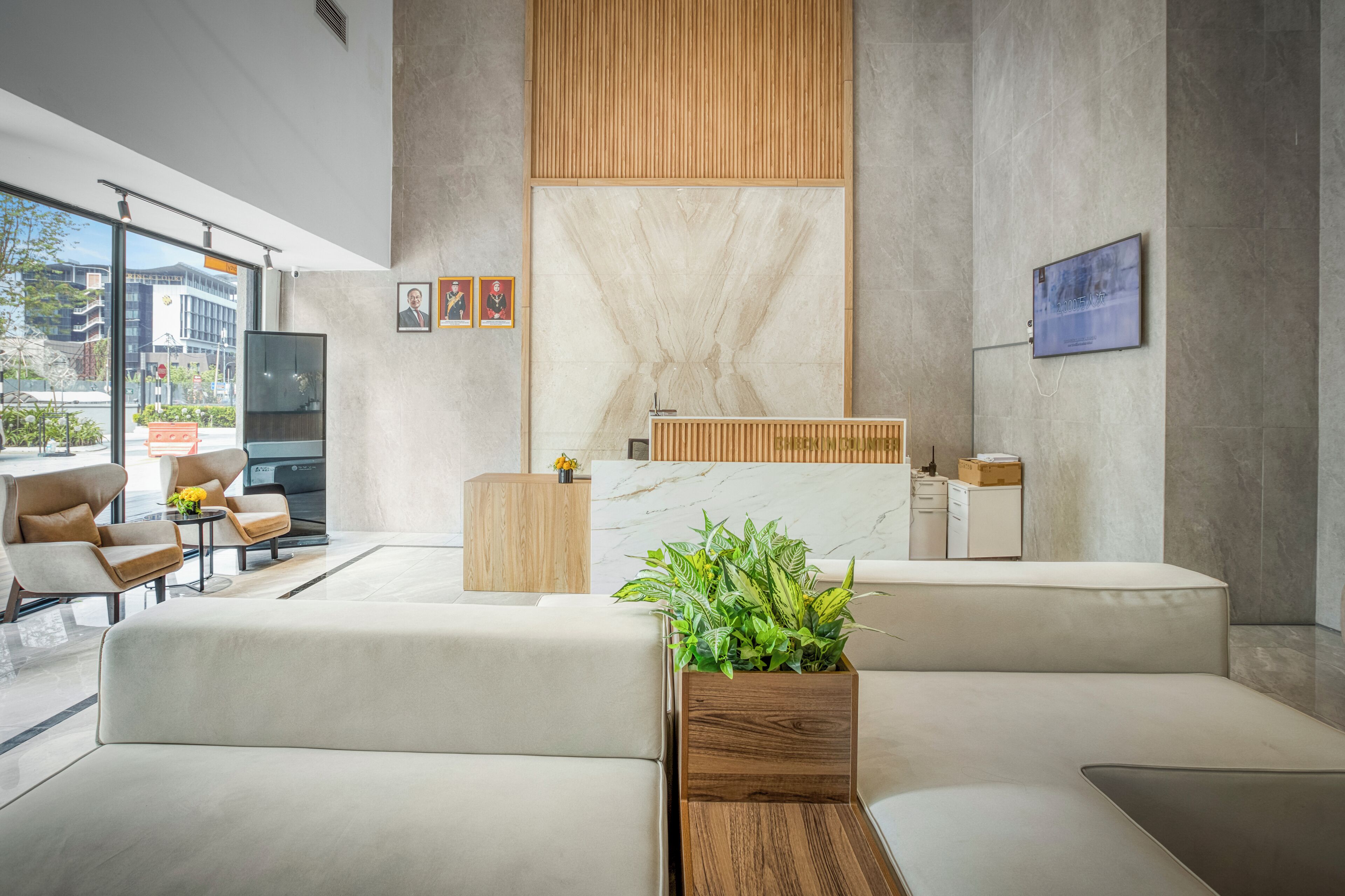 A modern reception area with a sofa, wooden reception desk, and a plant.