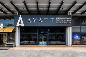 Η εξωτερική όψη του κτιρίου Ayatt Apartments Servis Bukit Bintang, με τον μοντέρνο σχεδιασμό του, τα μεγάλα γυάλινα παράθυρα και το εμφανές λογότυπο.