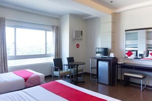 Quarto de hotel com duas camas, uma escrivaninha, televisão e janela com cortinas.