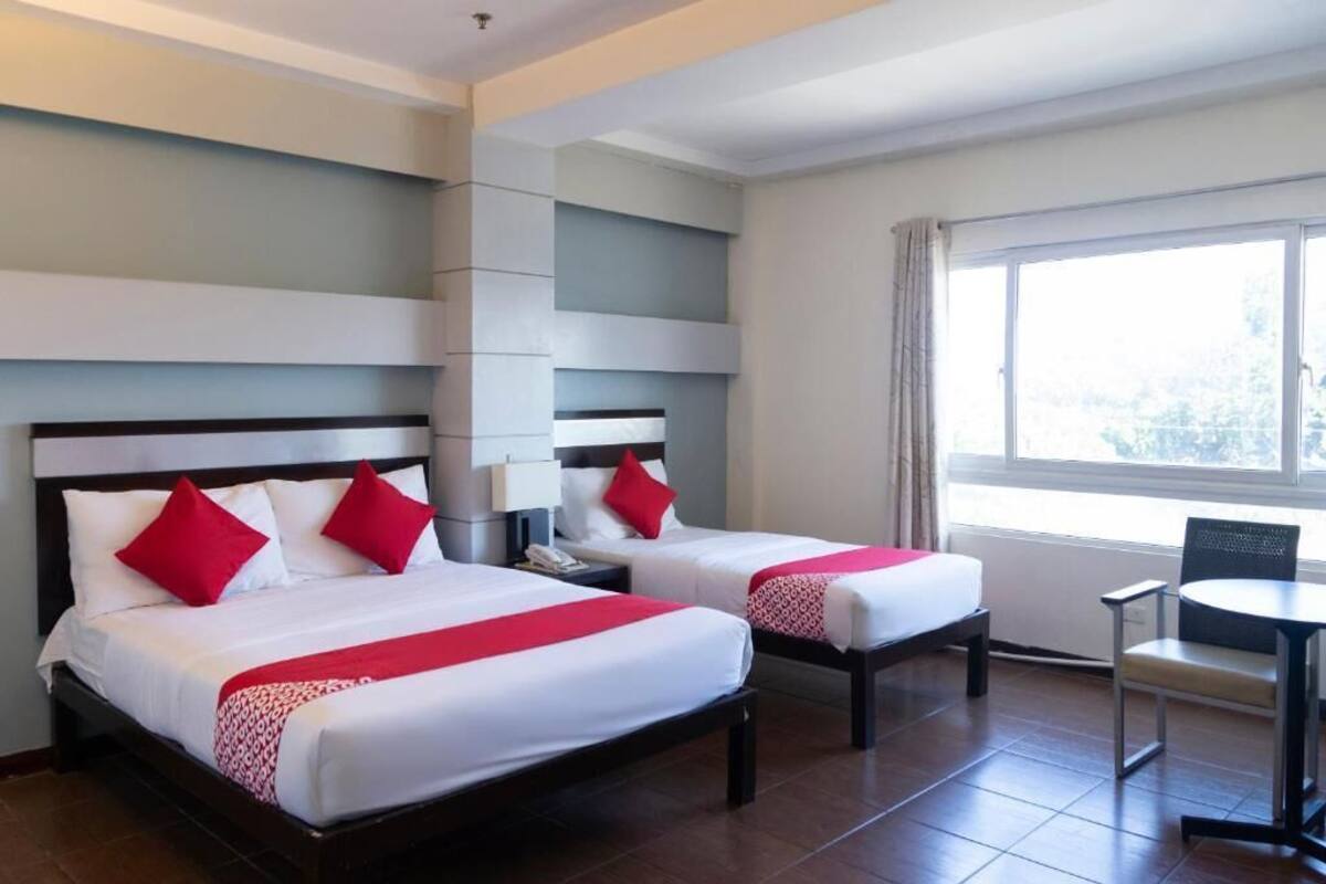 A hotel room with two beds, a small table, and a chair.