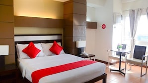 A hotel room with a bed, bedside tables, a chair, and a view of the outdoors. - EAST VIEW HOTEL (Bacolod)