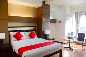 A hotel room with a bed, bedside tables, a chair, and a view of the outdoors.