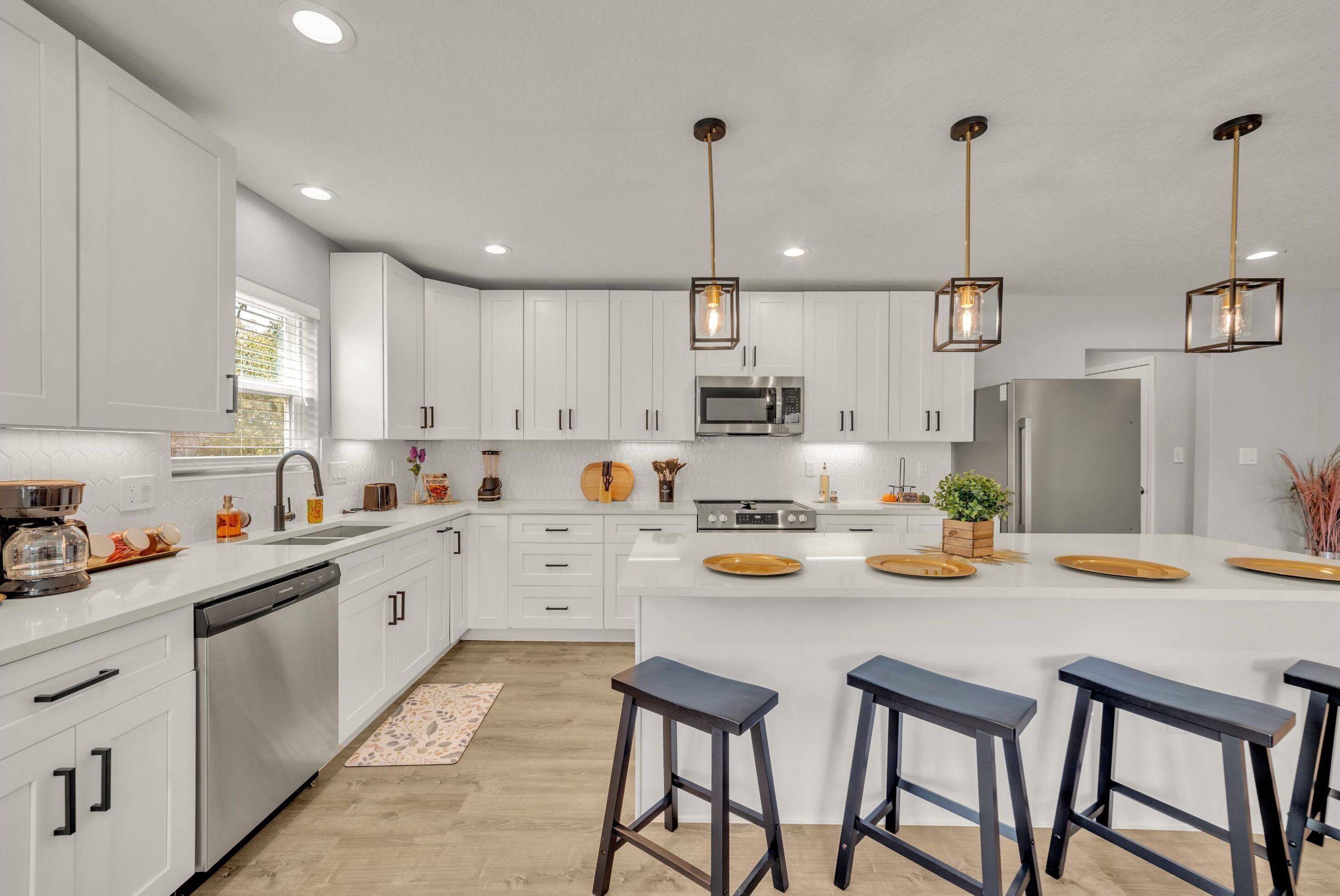 A modern kitchen with white cabinets, stainless steel appliances, and a central island with stools.