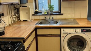 Une cuisine de taille réduite, équipée d’un évier, d’une cuisinière et d’un lave-linge.