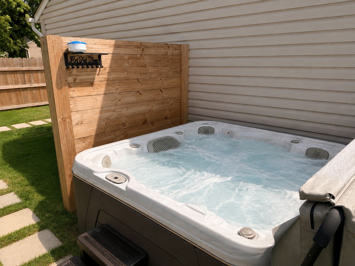 A hot tub with a wooden enclosure, a control panel, and a label that reads 'Hot Tub Time.'