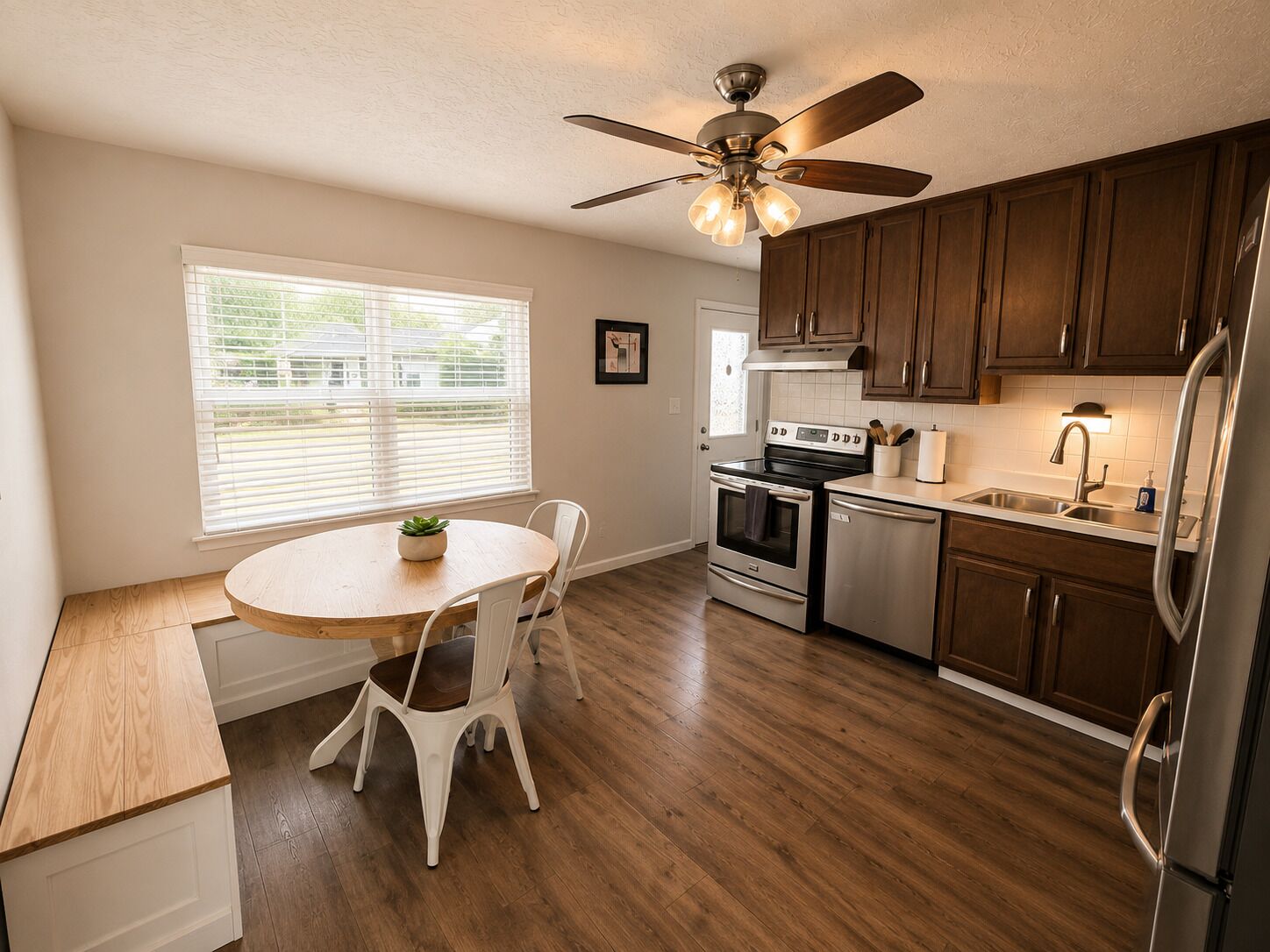 A kitchen with wooden cabinets, a stove, a refrigerator, and a ceiling fan.