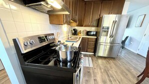 A modern kitchen with a black stove, stainless steel appliances, wooden cabinets, and a tiled backsplash.