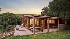 Una cabaña de madera con un balcón, una mesa de picnic y una banca.