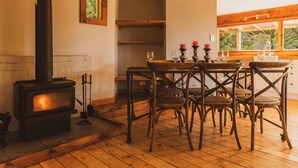 Una habitación acogedora con chimenea de leña, una mesa de comedor de madera y sillas.