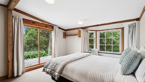 Un dormitorio con una cama grande, vigas de madera, una ventana con cortinas y vistas al exterior.
