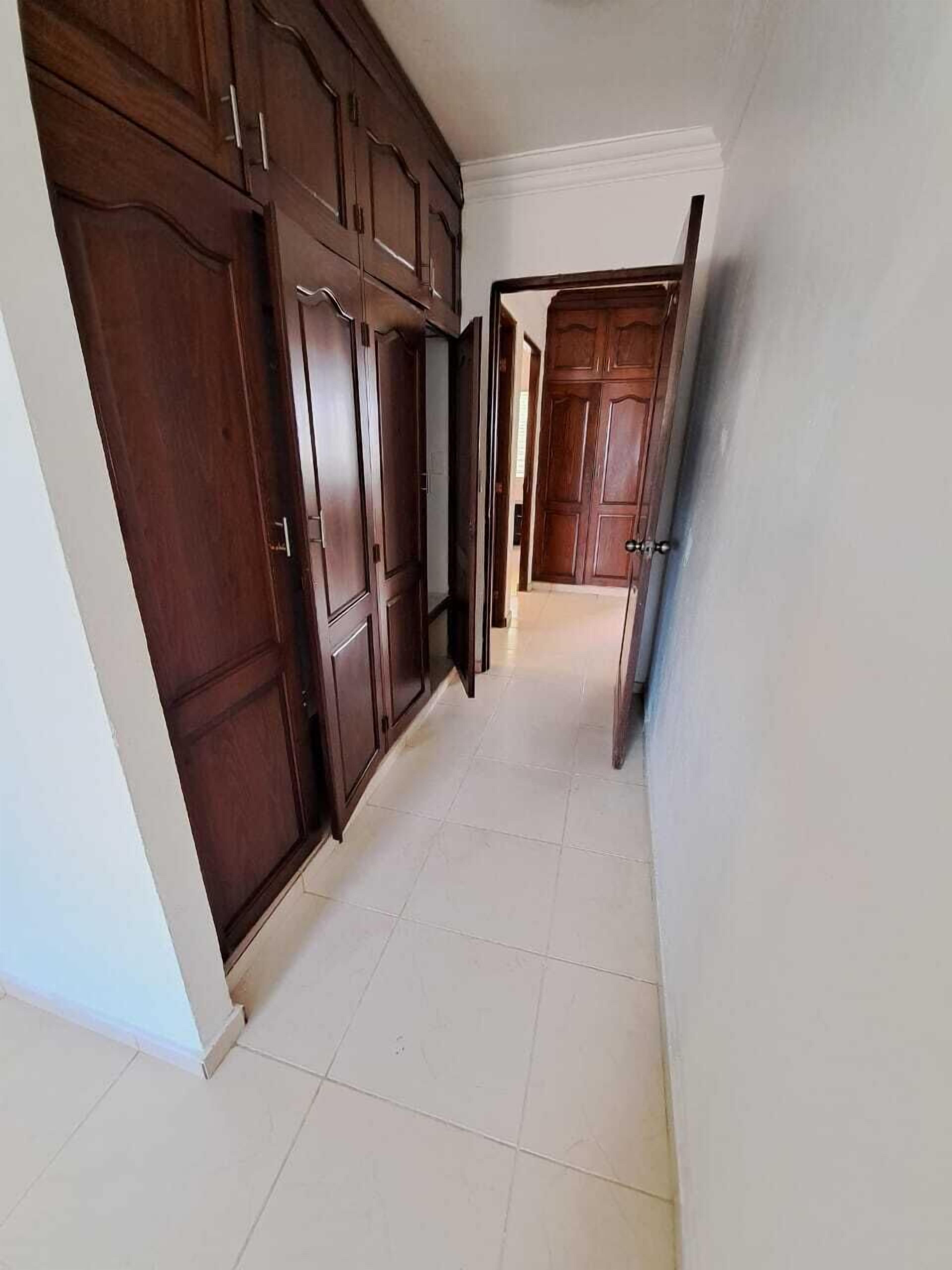 A hallway with dark wooden cabinets and a tiled floor.