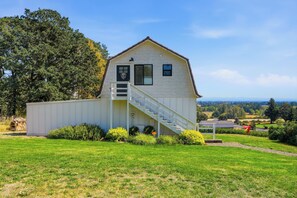 Un bâtiment blanc avec un escalier, entouré de verdure et sous un ciel dégagé.