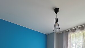 Un dormitorio con una cama grande, una mesita de noche, una lámpara y una ventana con cortinas.