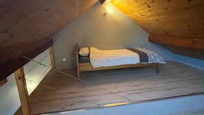 A loft-style bedroom with a sloped ceiling and exposed wooden beams.